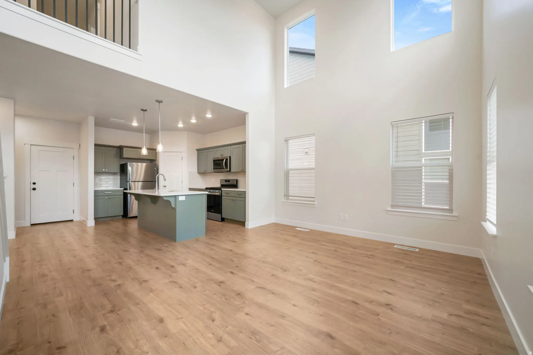 Expansive open-concept living area featuring high ceilings, wood-finish flooring, and multiple windows