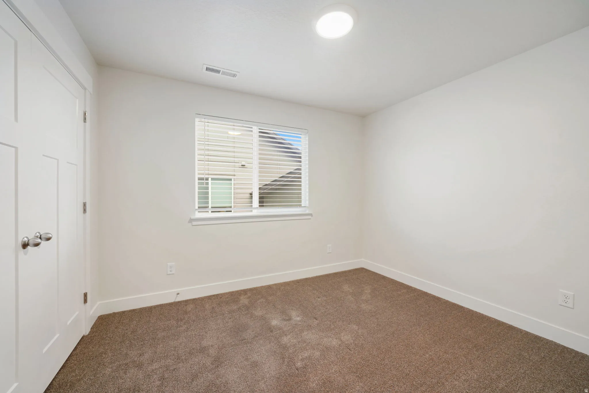 Neutral-toned wall-to-wall carpeting complements the white walls and trim