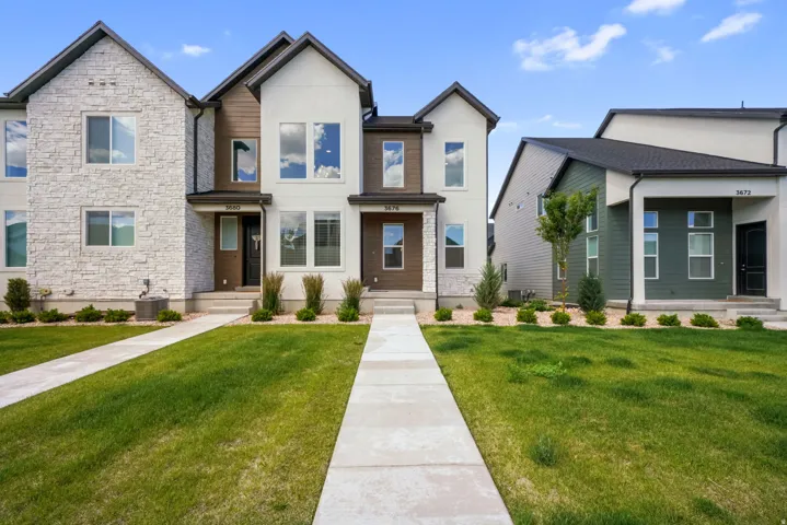 Contemporary townhome with a multi-textured facade featuring stone, stucco, and wood-finish siding