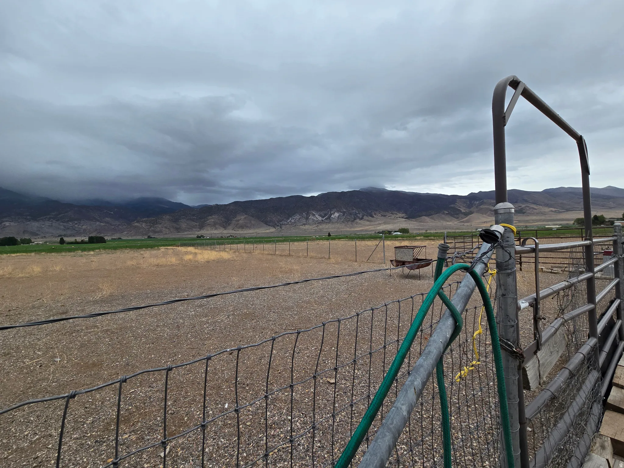 Expansive land parcel featuring fencing, an additional fenced enclosure, and distant mountain topography