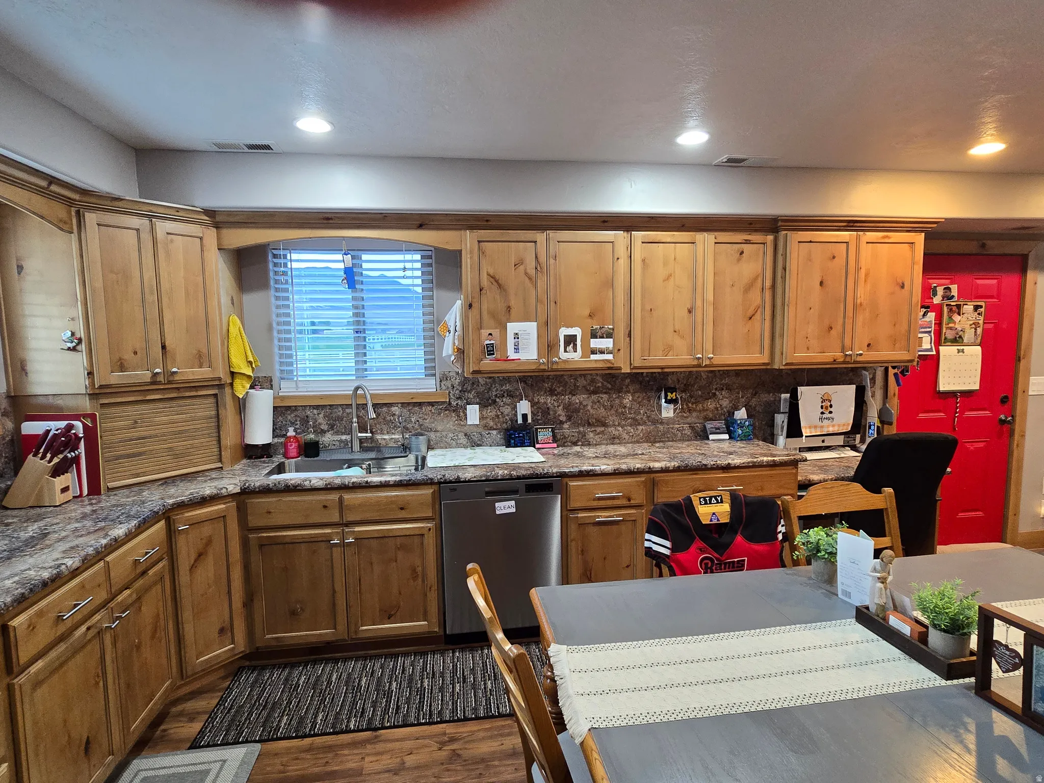 Kitchen featuring wood-finish cabinetry, speckled countertops, and a stainless steel dishwasher