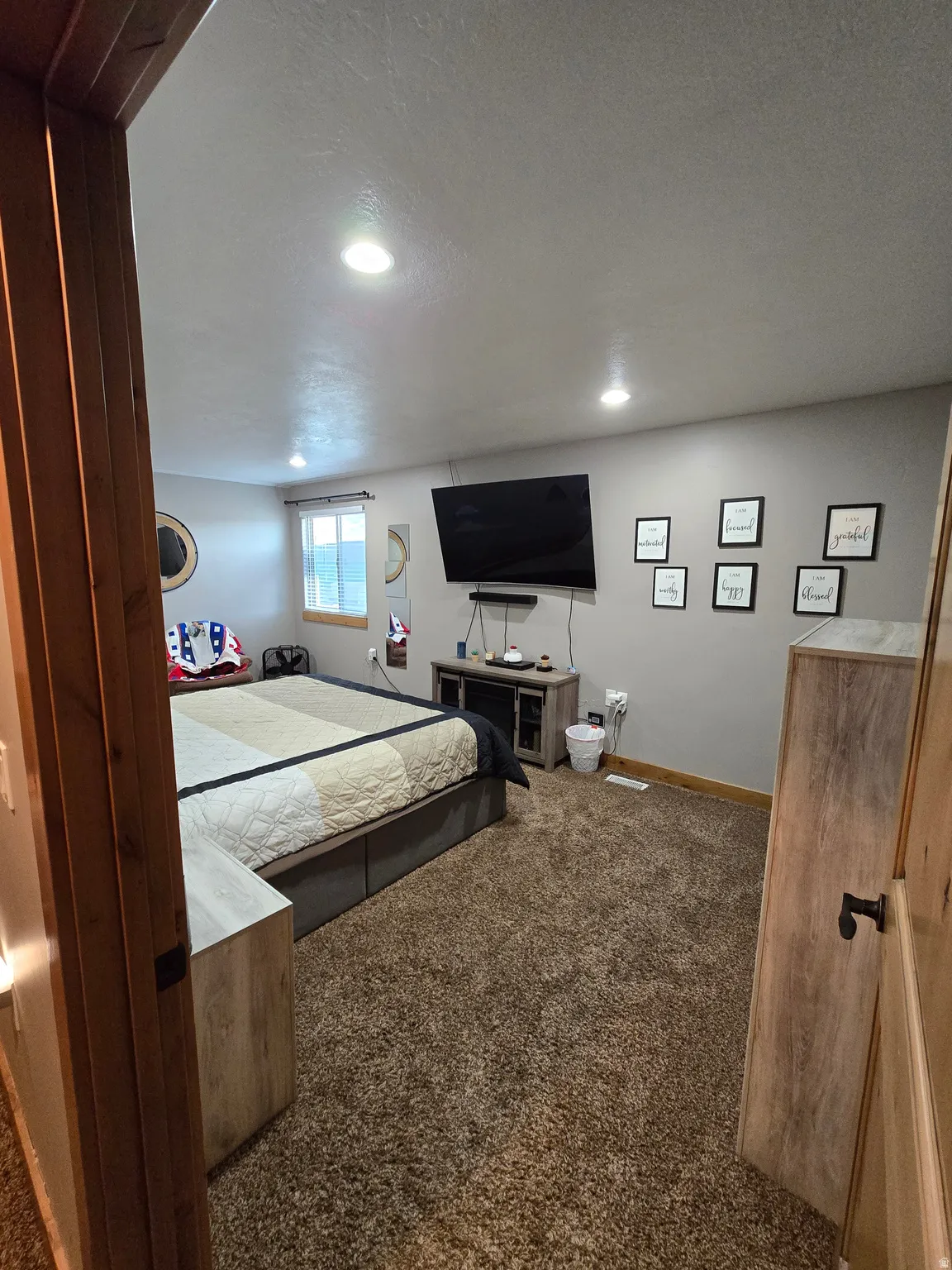 Carpeted bedroom with recessed lighting, a window, and wood-finish trim