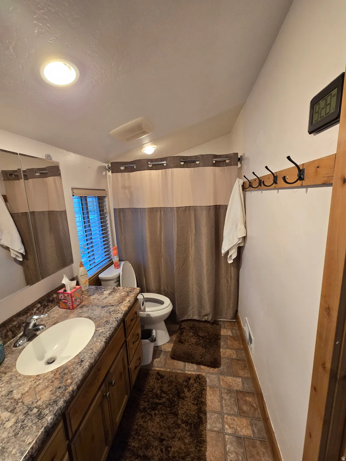 Bathroom featuring a wood-finish vanity with a stone-look countertop, an oval undermount sink, and a chrome faucet