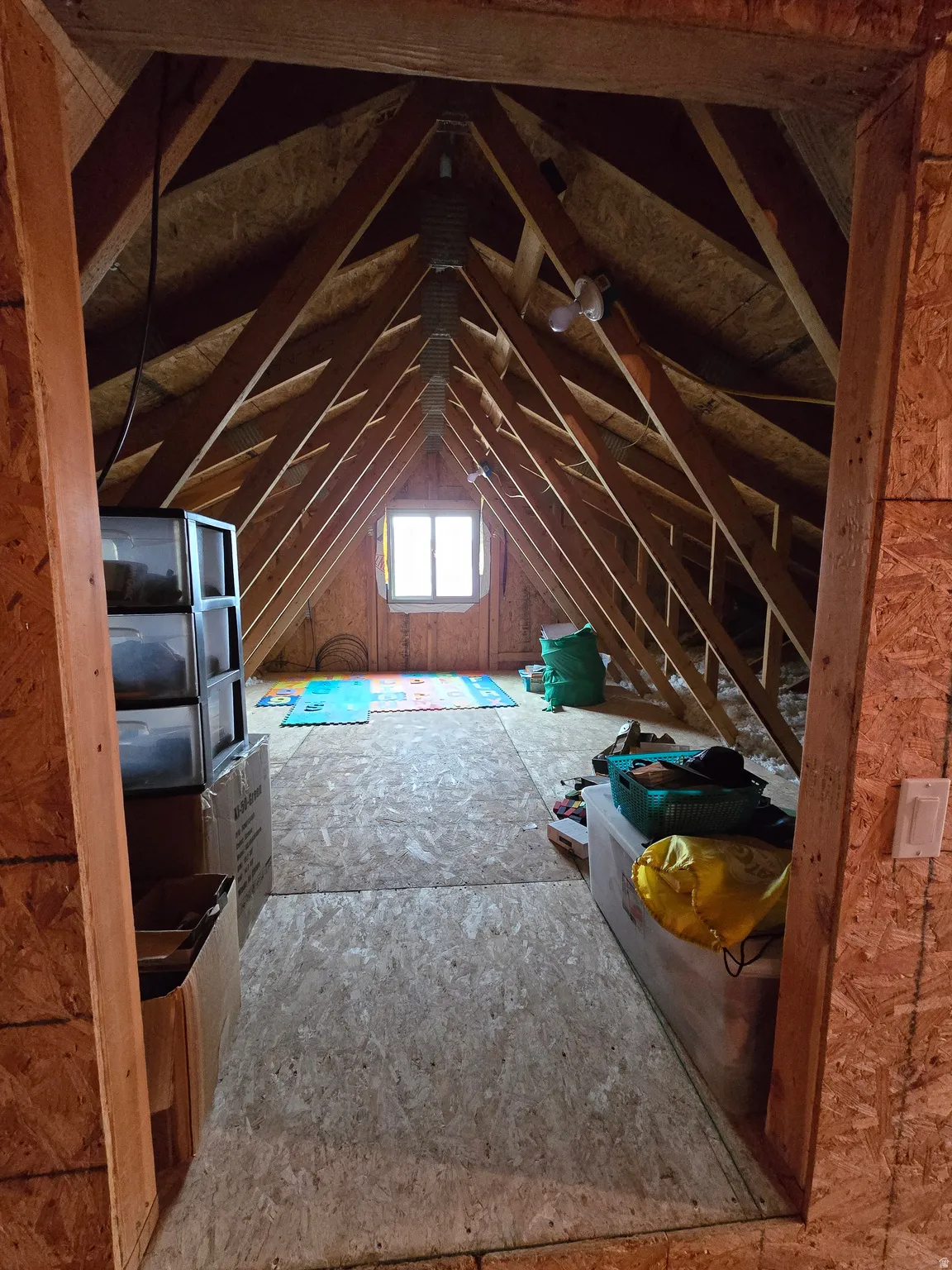 Attic space featuring exposed wood framing, wood-finish flooring, and a central window