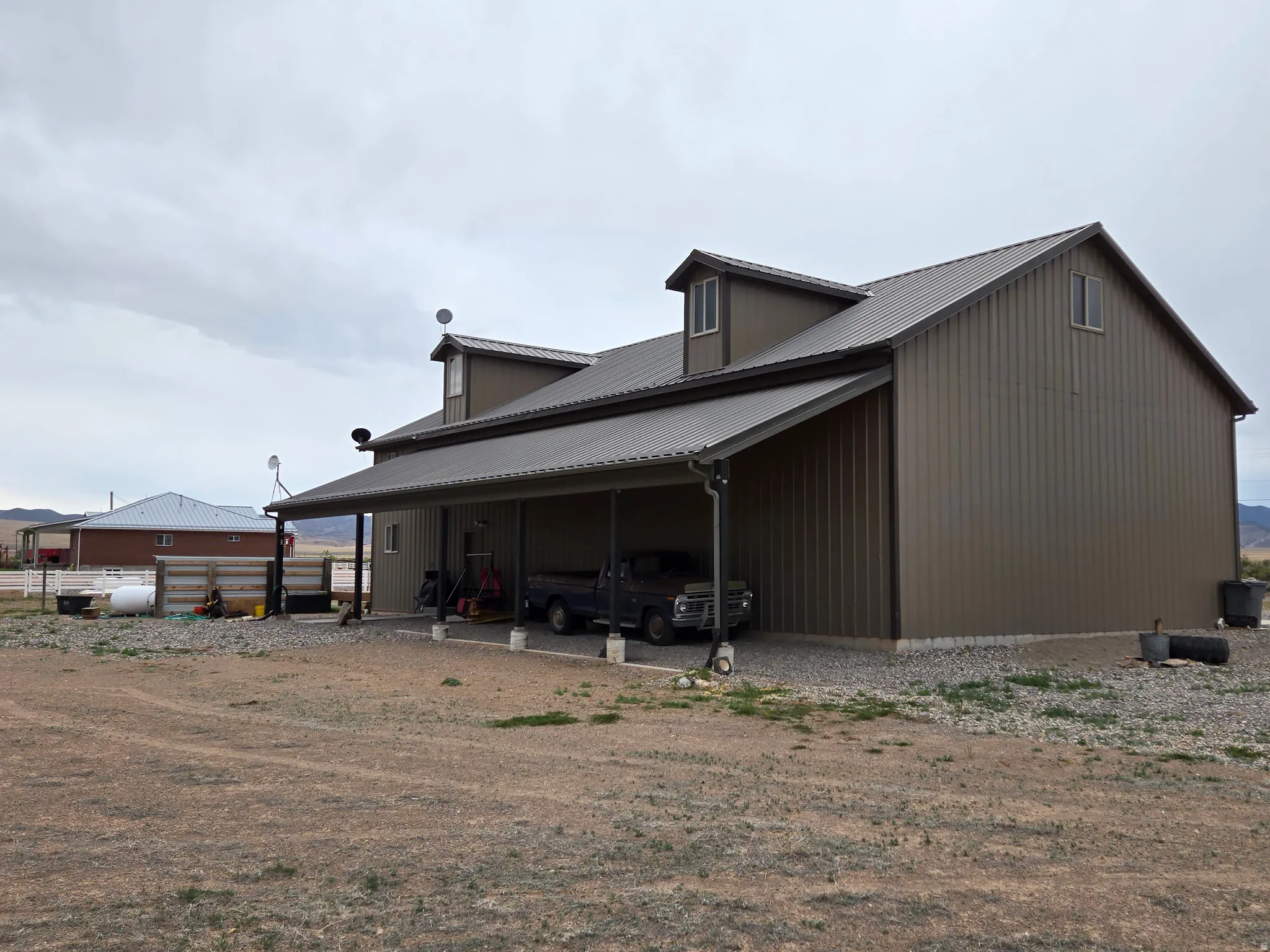 Exterior featuring a metal roof, dormer windows, a covered carport, and vertical panel siding
