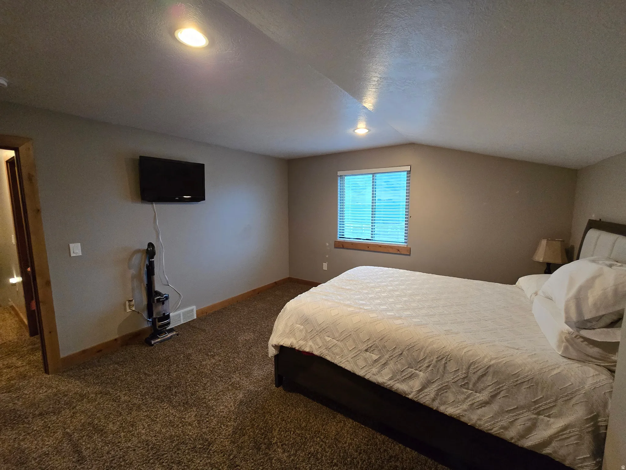 Carpeted room featuring a window with blinds, recessed lighting, and an angled ceiling