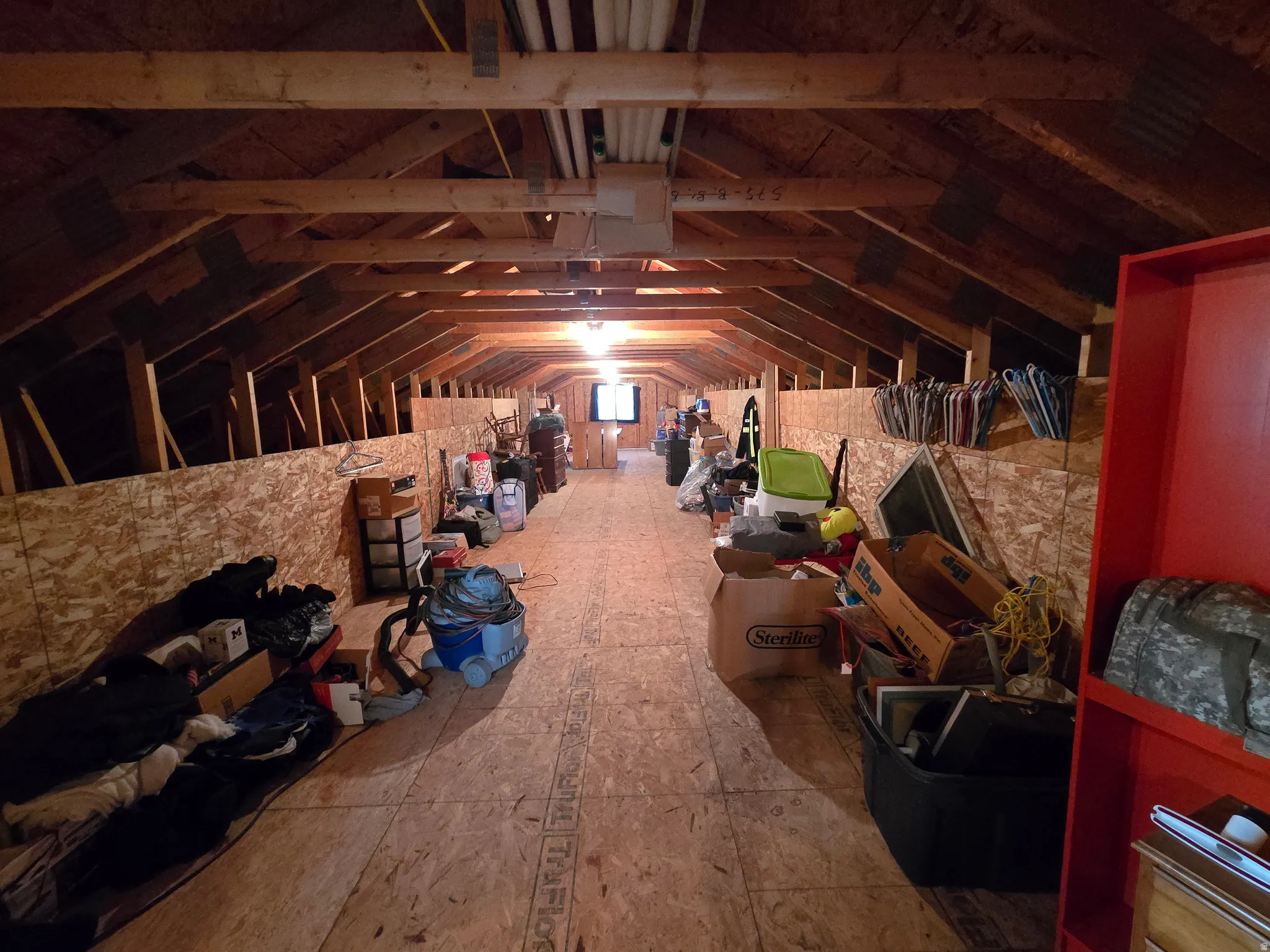 Attic space featuring exposed wood beams and plywood flooring