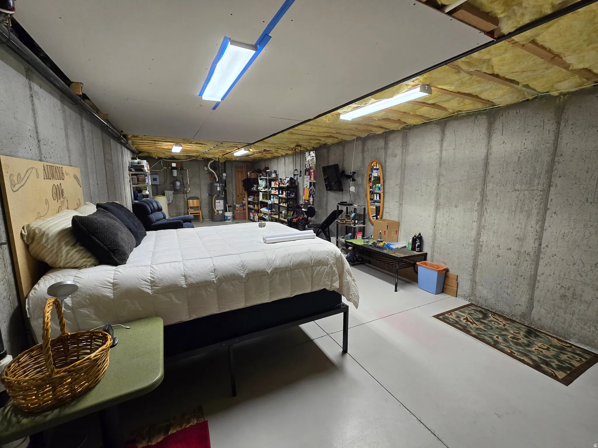 Unfinished basement space featuring concrete walls, concrete flooring, and exposed ceiling joists with insulation
