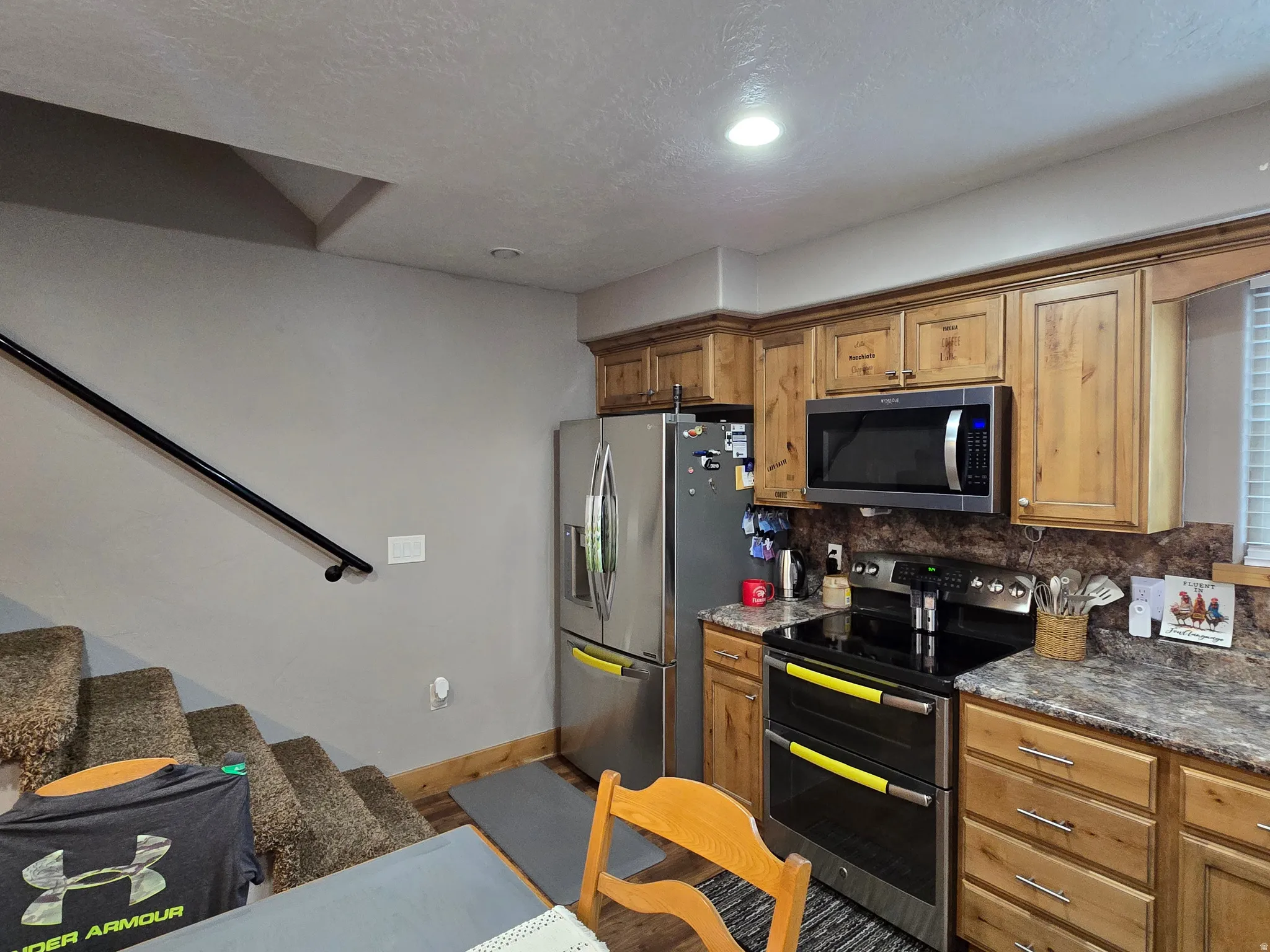Kitchen featuring wood-finish cabinetry, stainless steel appliances, and a textured laminate countertop