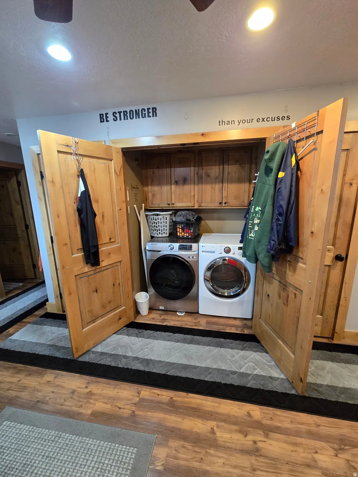 Dedicated laundry area featuring wood-finish flooring and integrated cabinetry