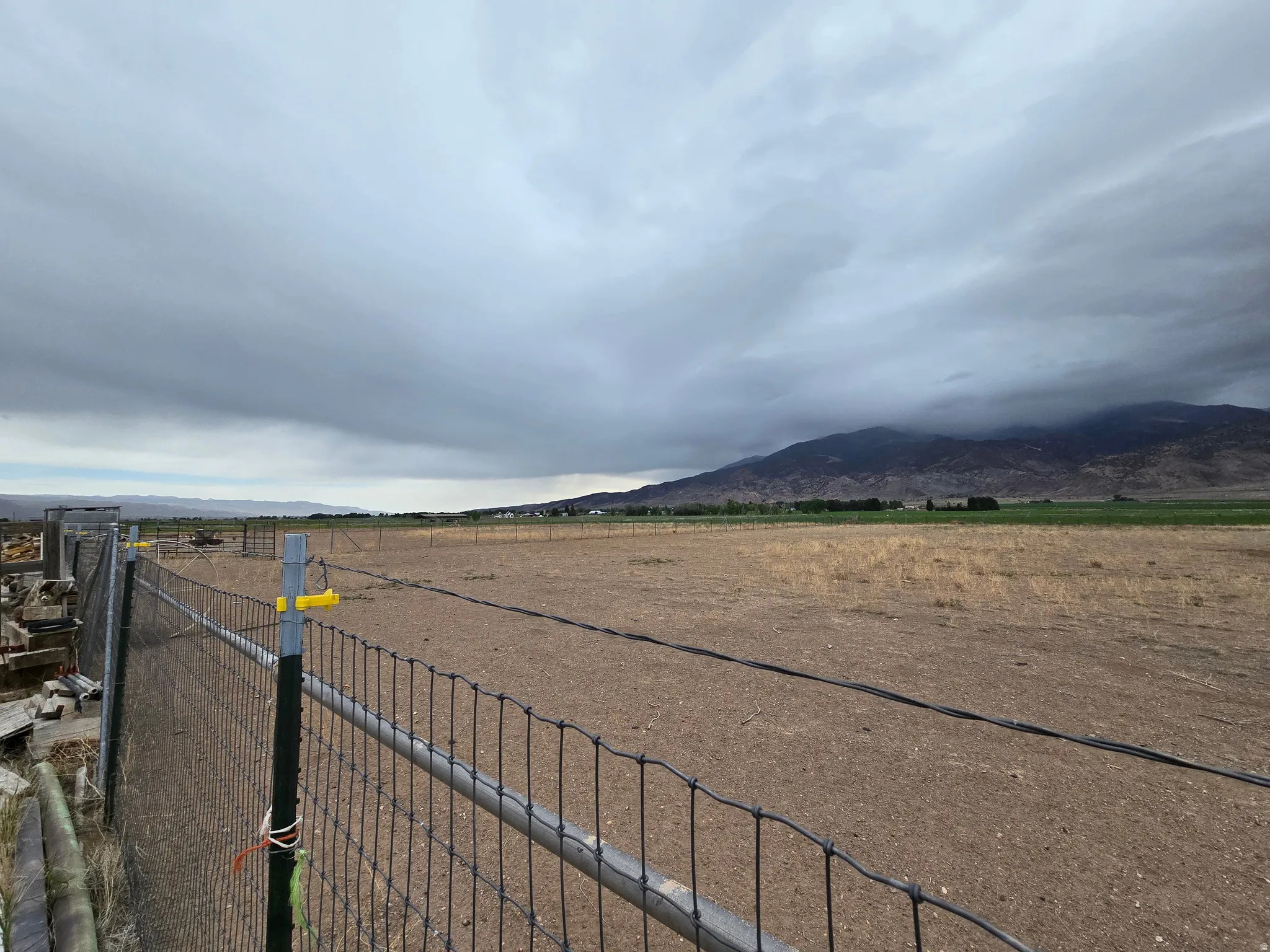 Expansive open land featuring a wire fence border and distant mountain scenery