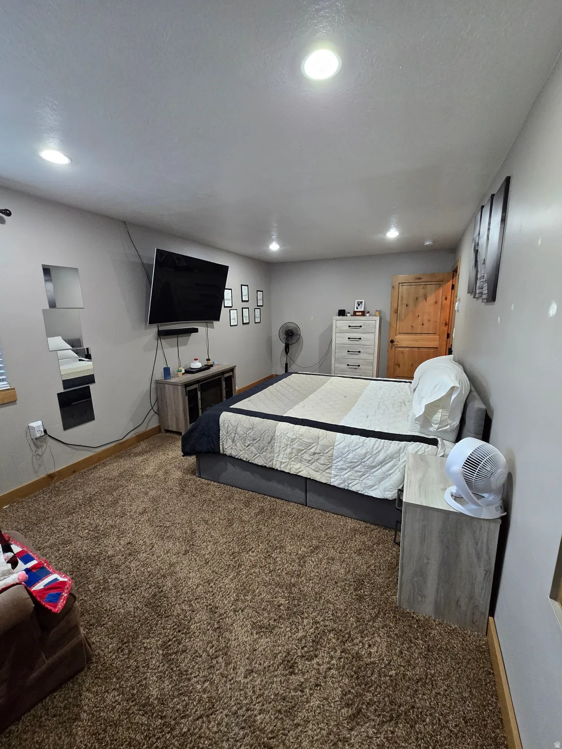 Recessed lighting illuminates this carpeted interior space, featuring a wood-panel door and light gray walls
