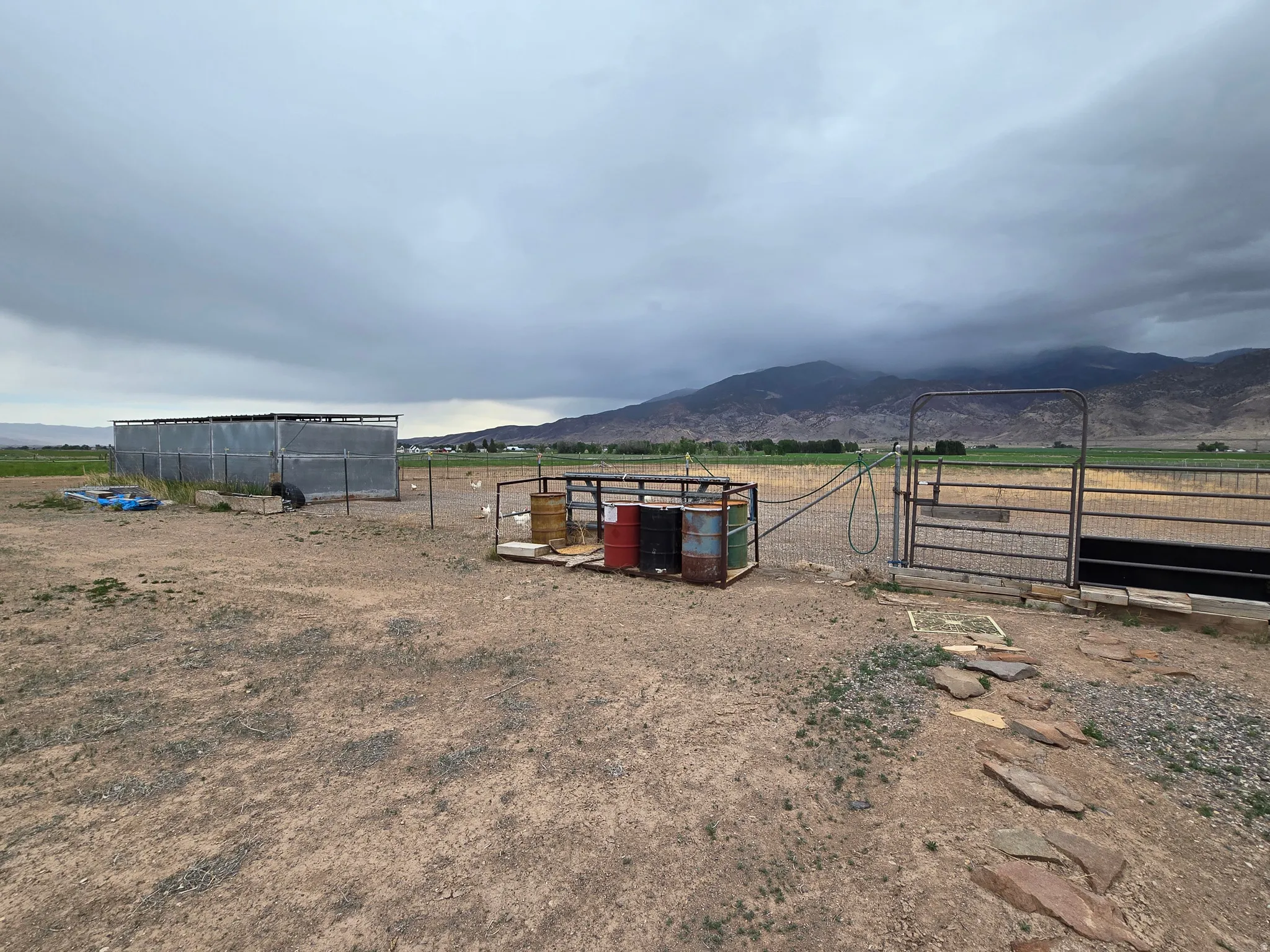 Expansive land parcel featuring a metal-sided outbuilding, a fenced enclosure, and a stone stepping path
