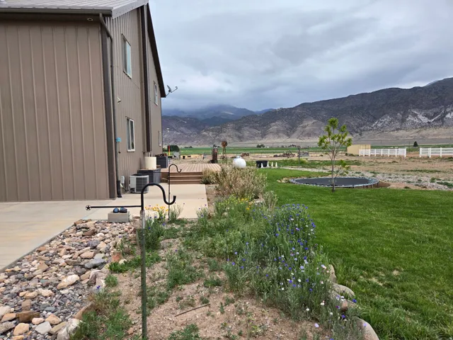 Expansive exterior featuring a brown metal-sided structure, concrete patio, wooden deck, and a lush lawn
