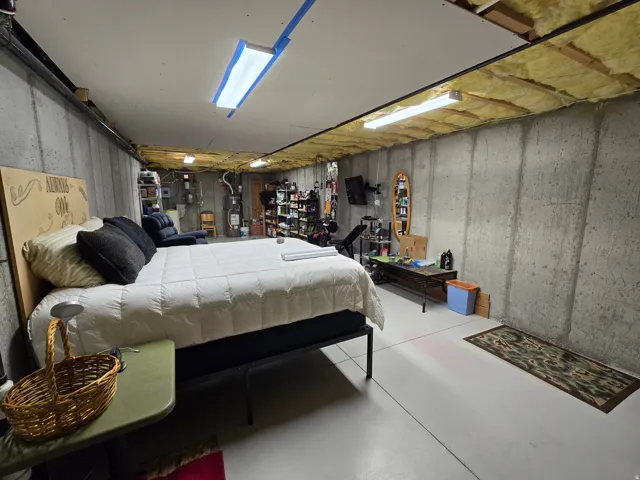 Unfinished basement space featuring concrete walls, concrete flooring, and exposed ceiling joists with insulation