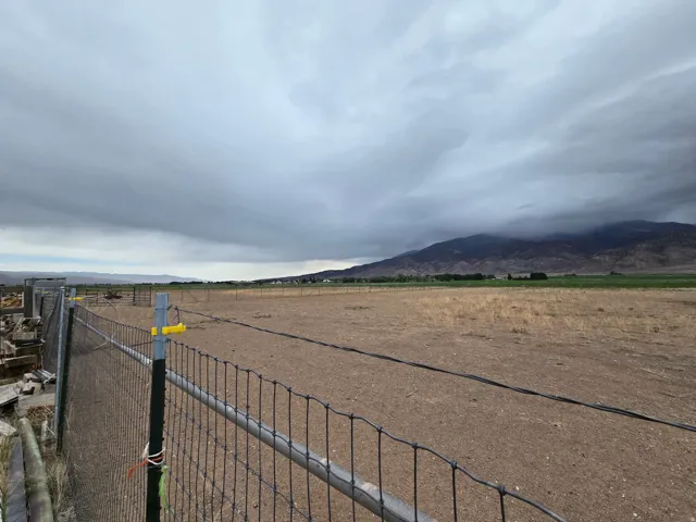 Expansive open land featuring a wire fence border and distant mountain scenery