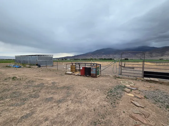 Expansive land parcel featuring a metal-sided outbuilding, a fenced enclosure, and a stone stepping path