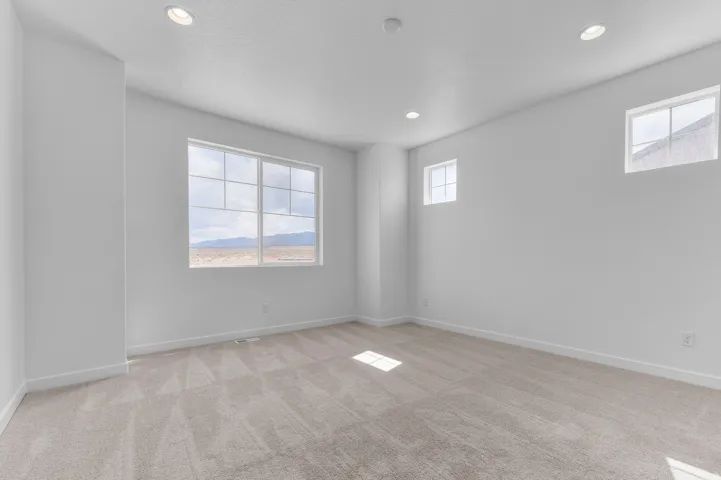 Spacious room featuring ample natural light from multiple windows, recessed ceiling lighting, and neutral carpeting