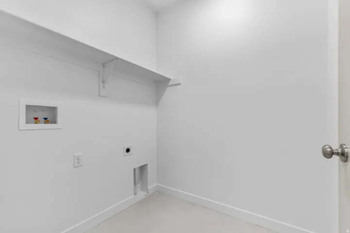 Dedicated utility area featuring a wall-mounted shelf, washing machine hookups, dryer vent, electrical outlet, and light tile flooring