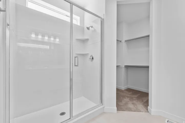 Glass-enclosed shower with a chrome shower head and built-in shelving