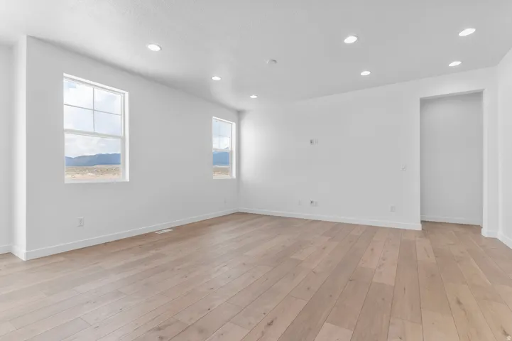 Expansive room featuring light wood-finish flooring, recessed lighting, and bright white walls