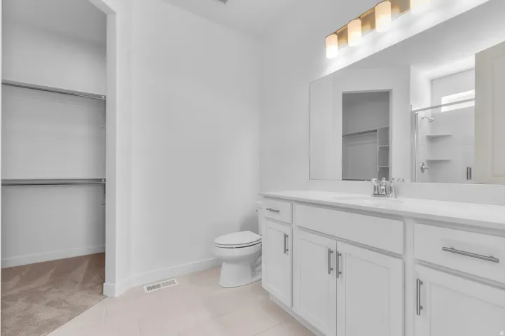 Bathroom featuring a double vanity with white cabinetry and a light-toned countertop