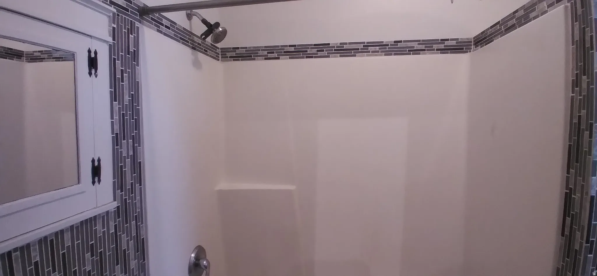 Shower with mosaic tile accents, integrated soap ledge, and chrome fixtures