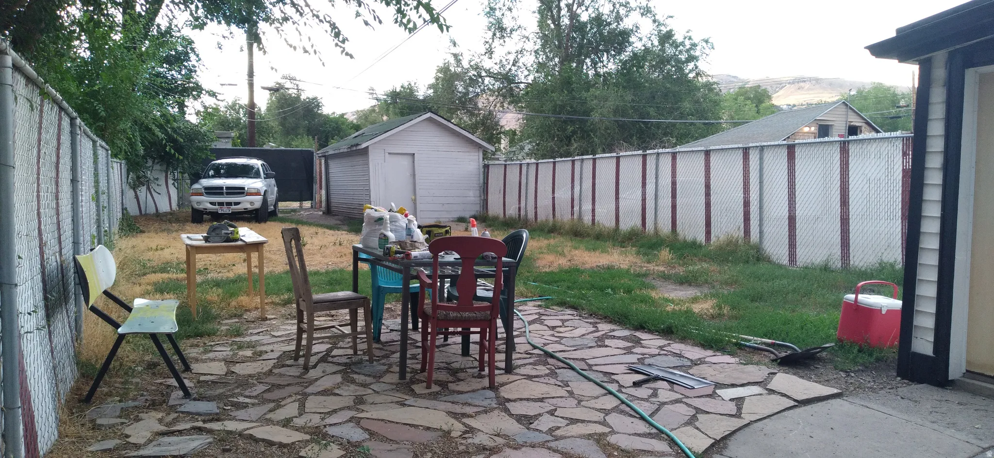 Expansive backyard featuring a natural stone patio and a detached shed