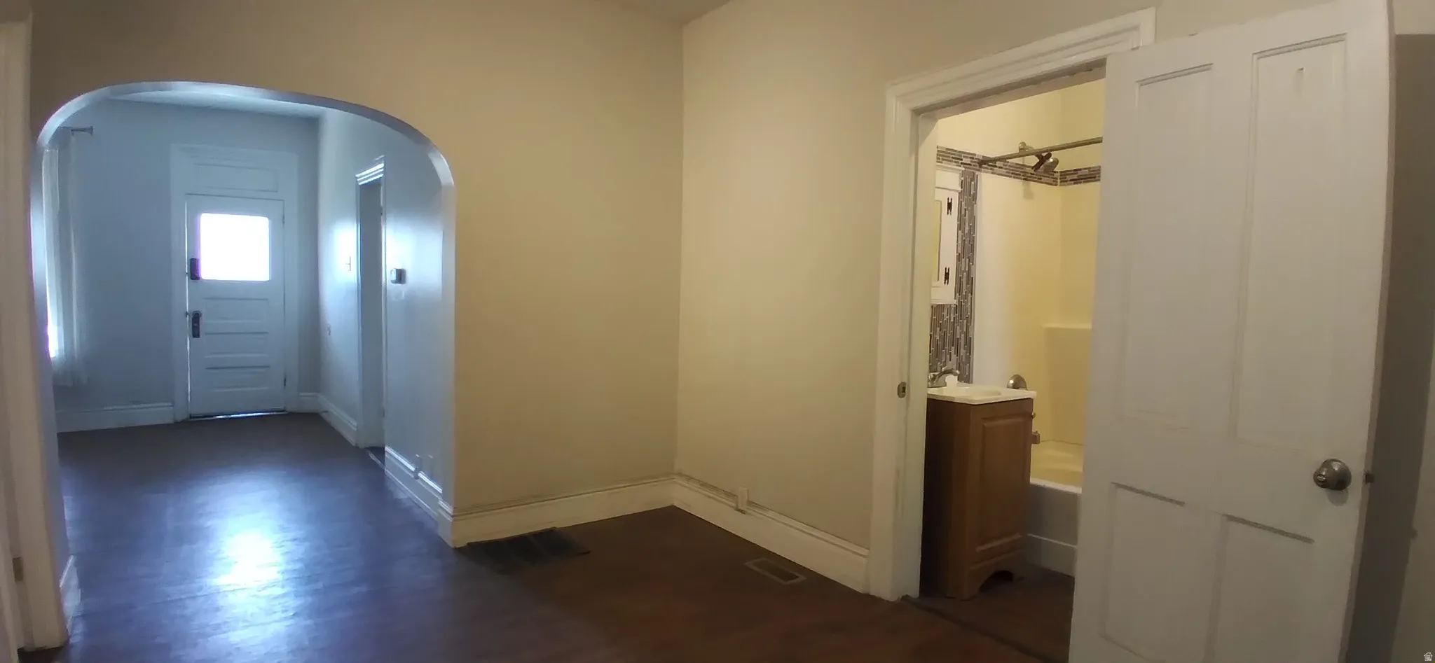 Archway entrance to additional room with white paneled door and natural light