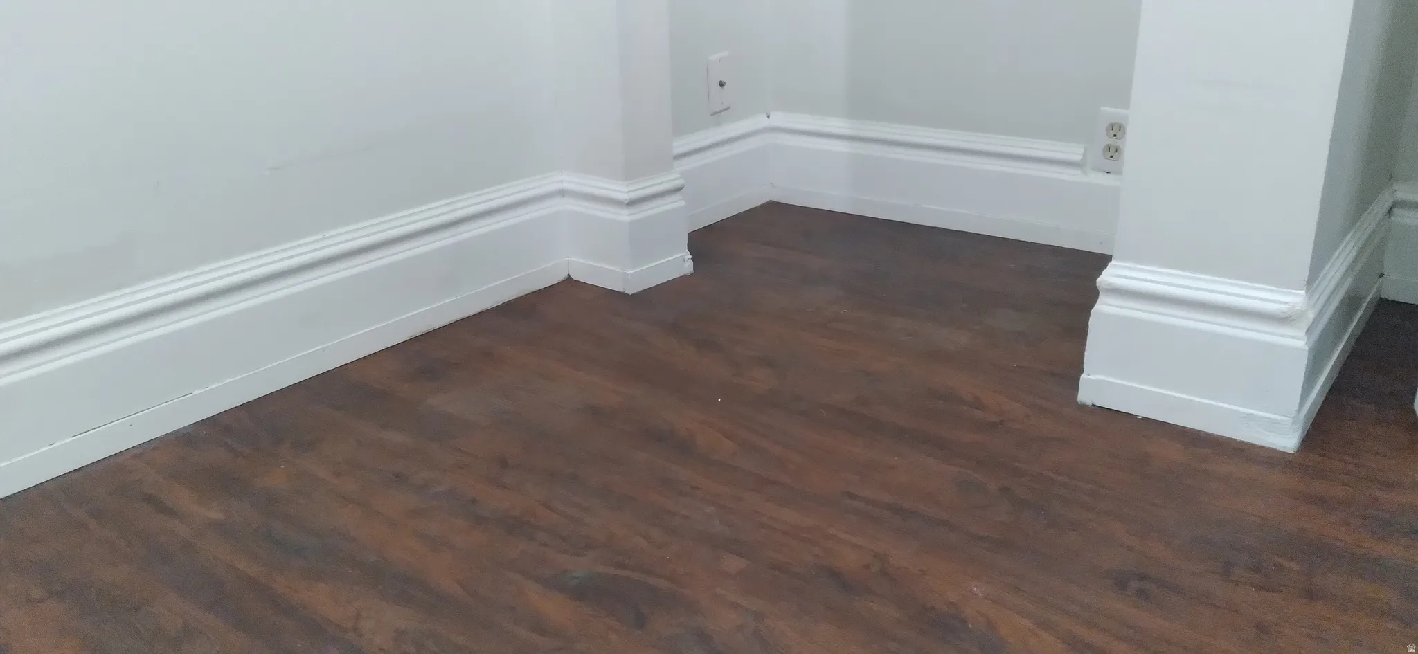 Rich wood-finish flooring complemented by substantial white baseboards and trim