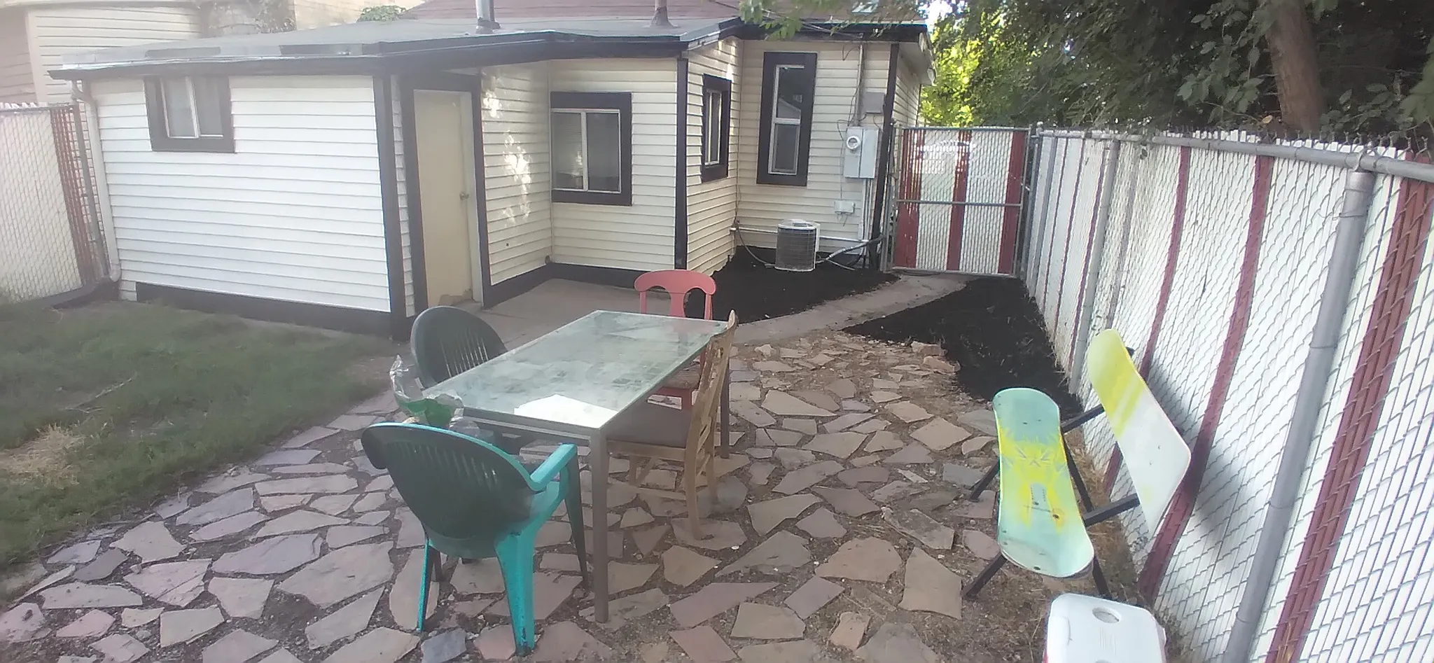 Paved patio area featuring irregular stone pavers, surrounded by a chain-link fence