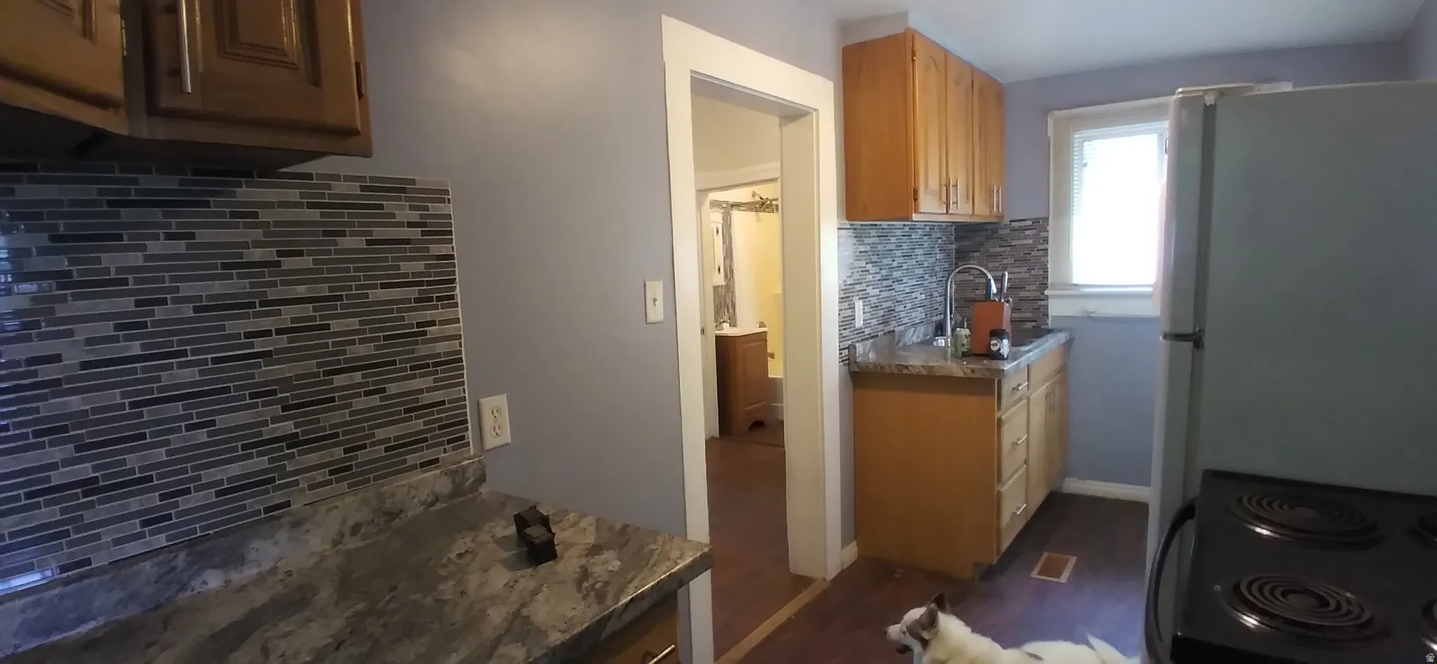 Kitchen featuring wood-finish cabinetry, a mosaic tile backsplash, and stone-look countertops