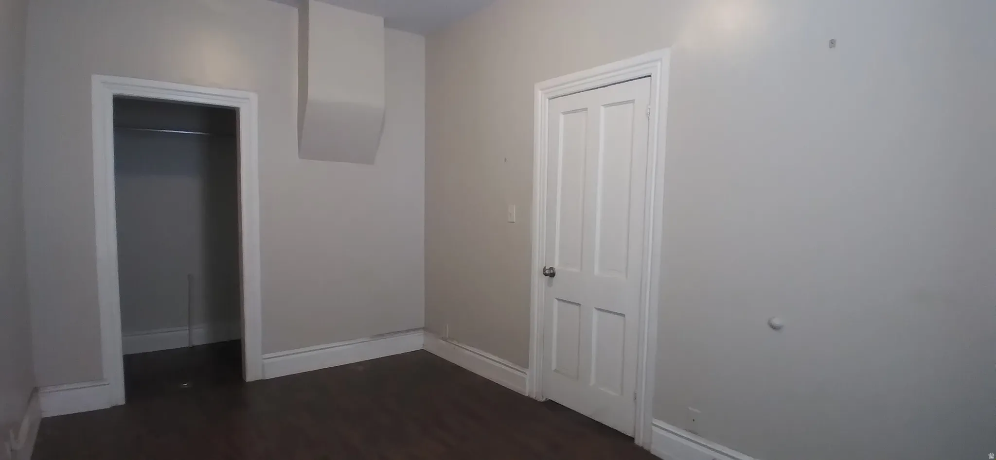 Room featuring dark wood-finish flooring, light neutral-toned walls, and white trim