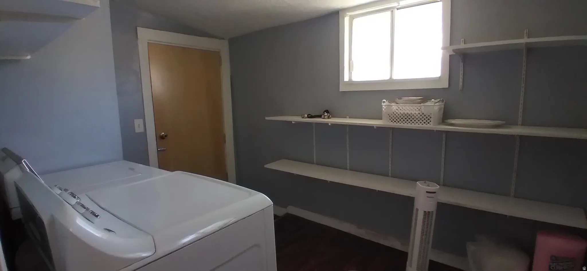 Utility room featuring dark wood-finish flooring, a light blue wall color, and a window providing natural illumination