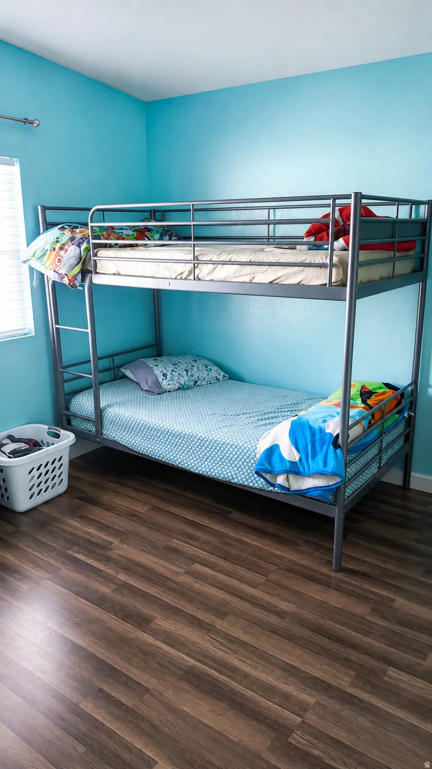 Room featuring wood-finish flooring, light blue walls, and a window with horizontal blinds