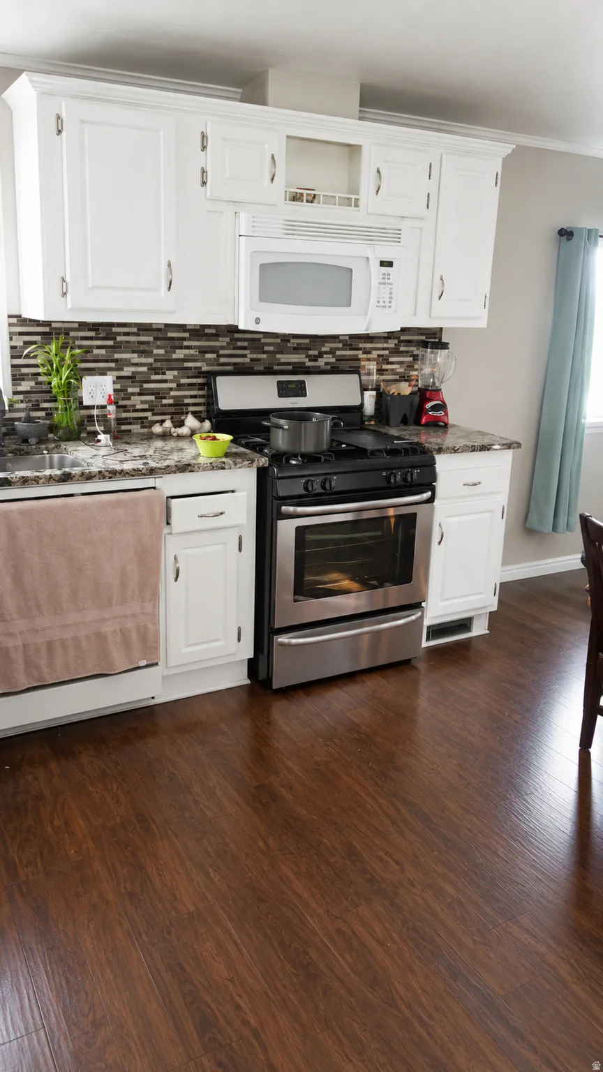 Kitchen featuring white cabinetry, a mosaic tile backsplash, granite-style countertops, wood-finish flooring, and stainless steel appliances including a range and over-the-range microwave