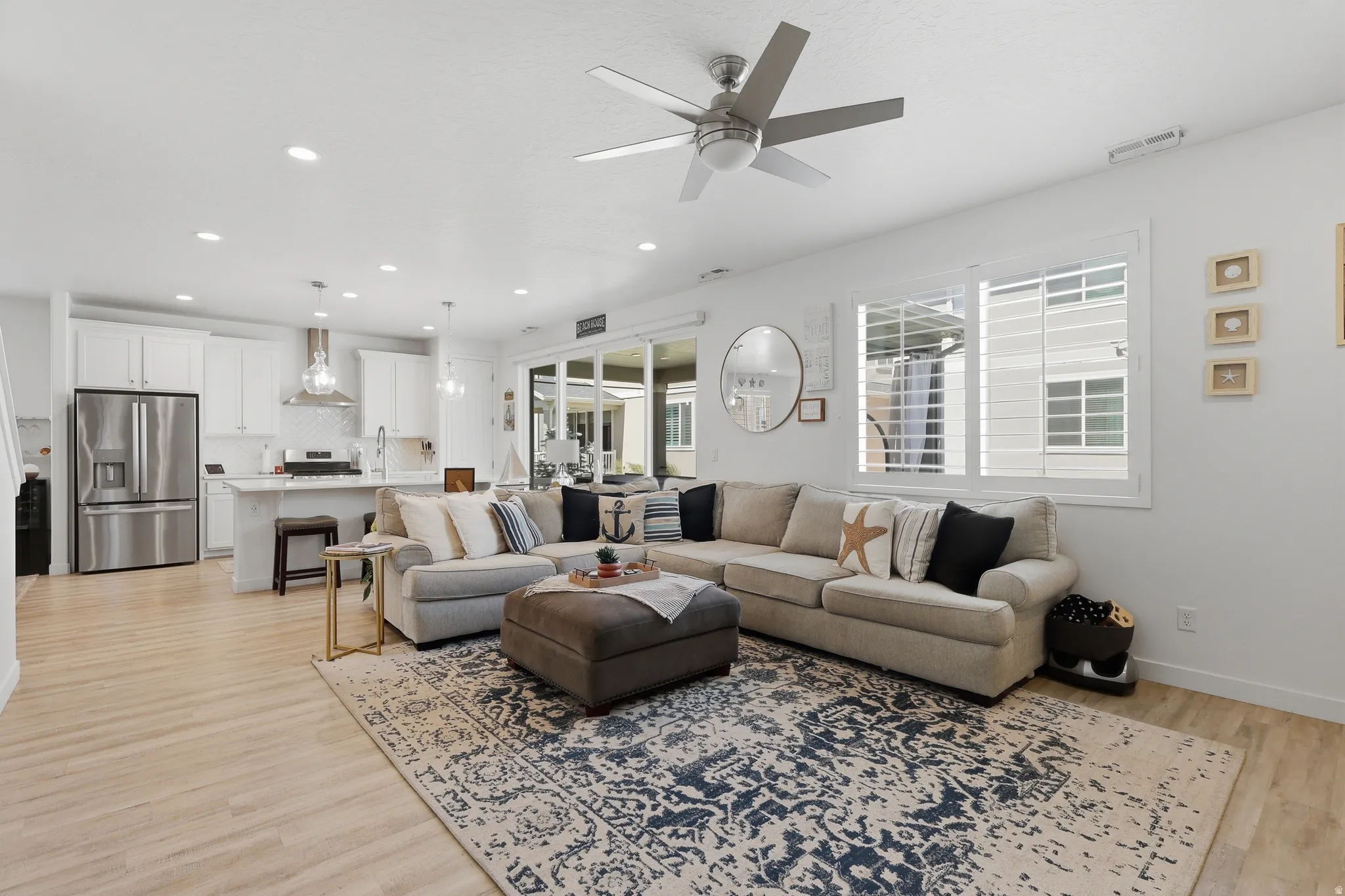 Recessed lighting with a ceiling fan, light wood-finish flooring, white kitchen cabinetry, stainless steel appliances, and sliding glass doors