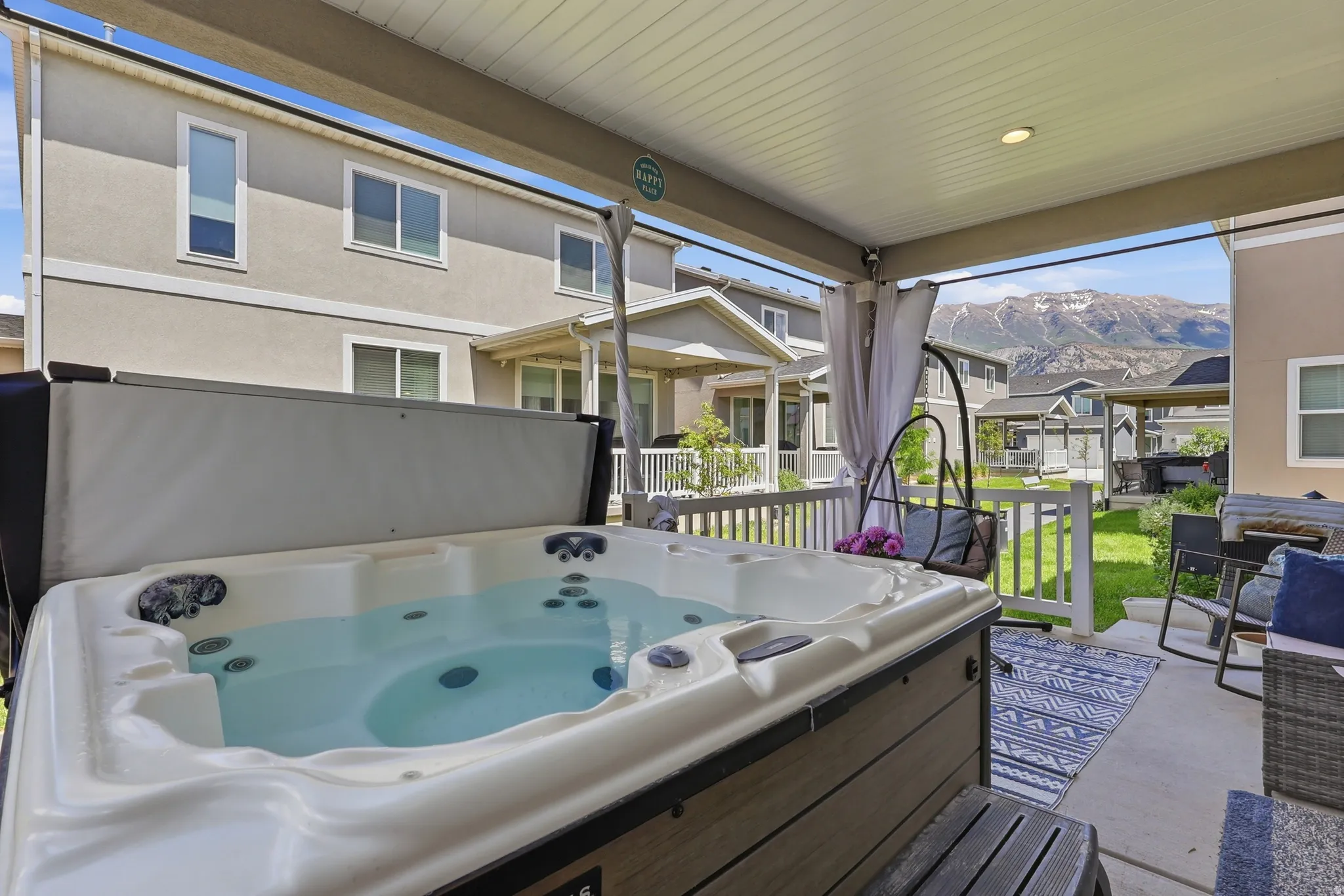 Covered patio featuring a built-in hot tub, white railing, and a stone-look patio floor