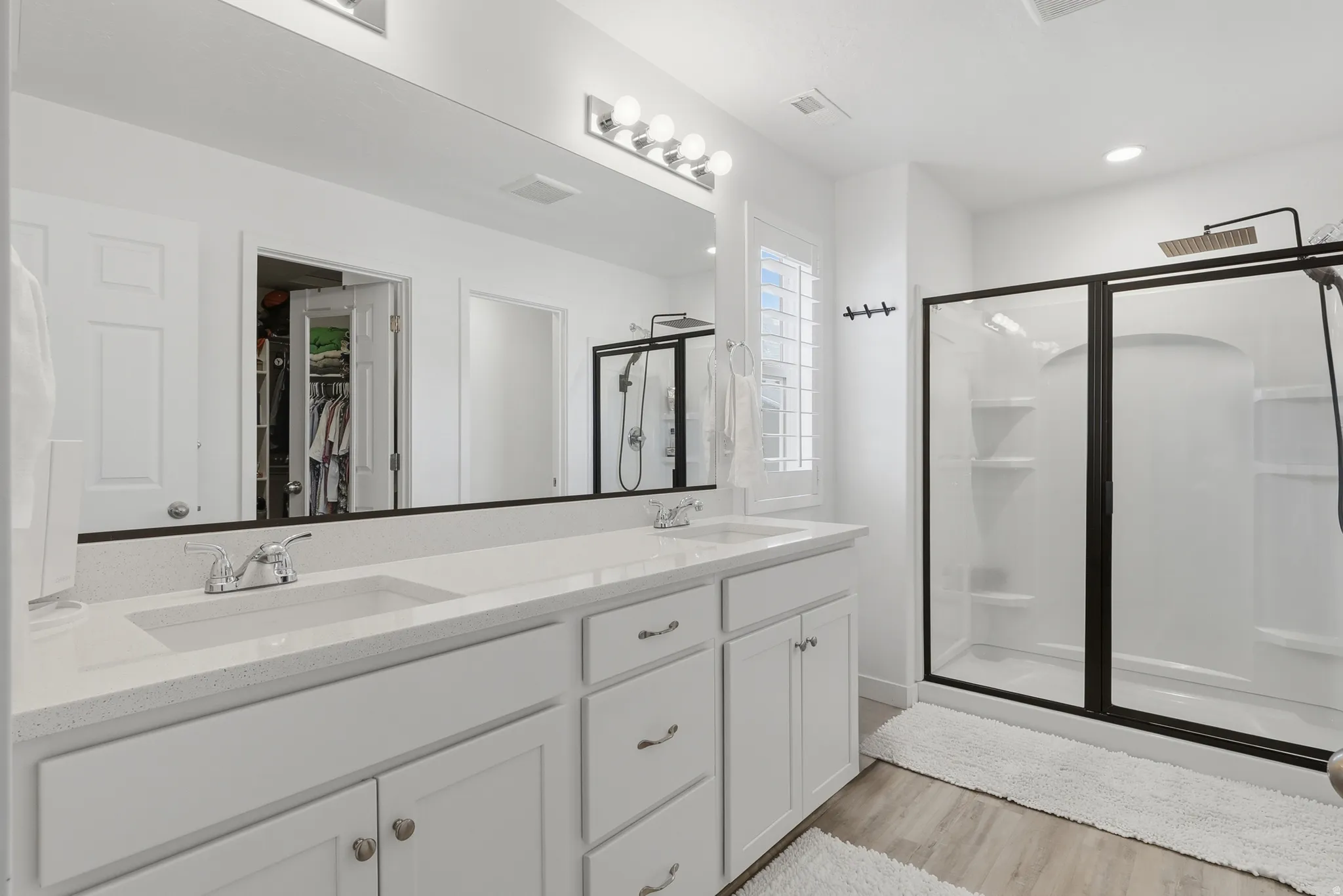 Bathroom featuring a dual vanity with white cabinetry and a light-toned countertop