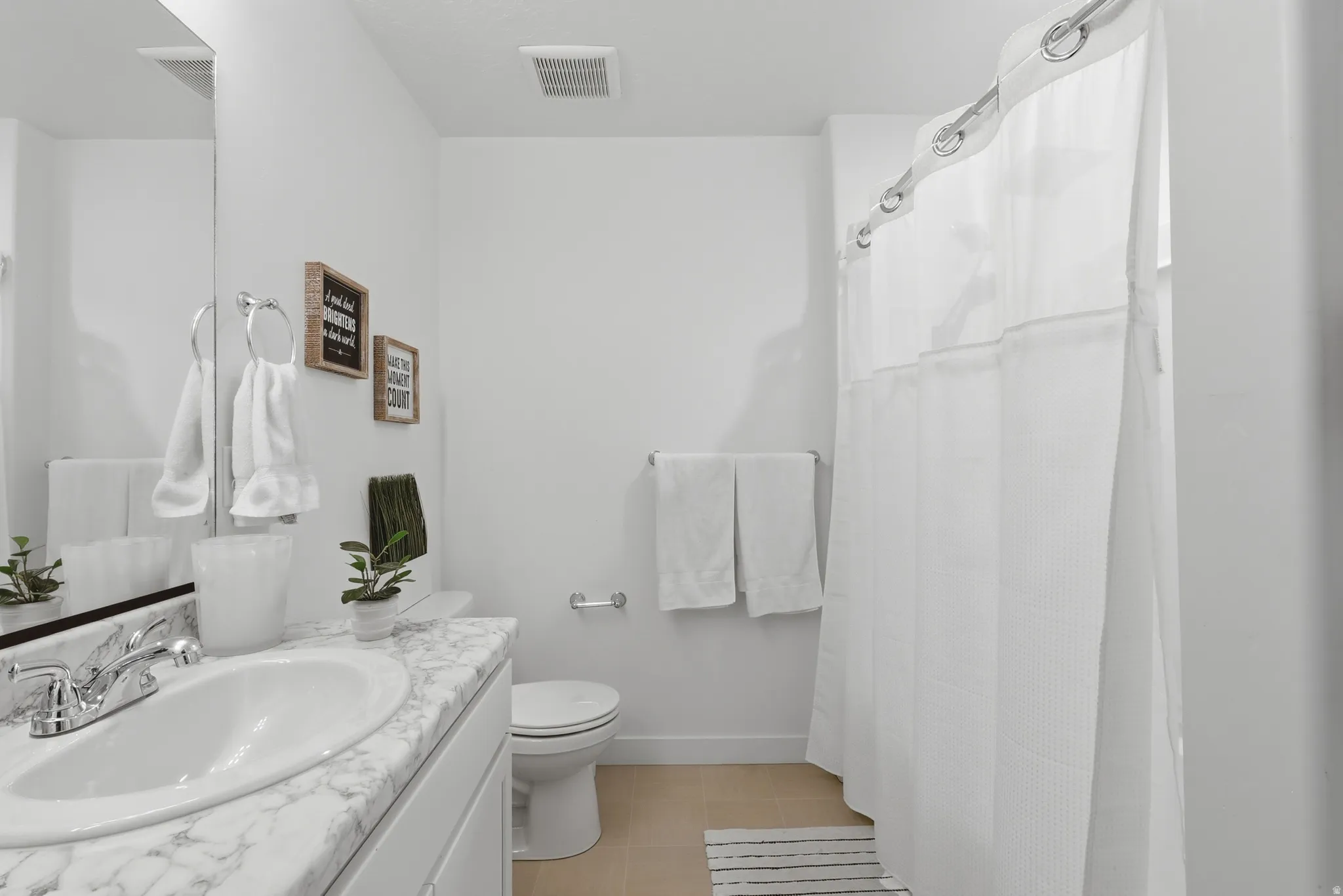 Bathroom featuring a white vanity with a marble-look countertop, an undermount sink with chrome fixtures, a toilet, and a shower with a white shower curtain
