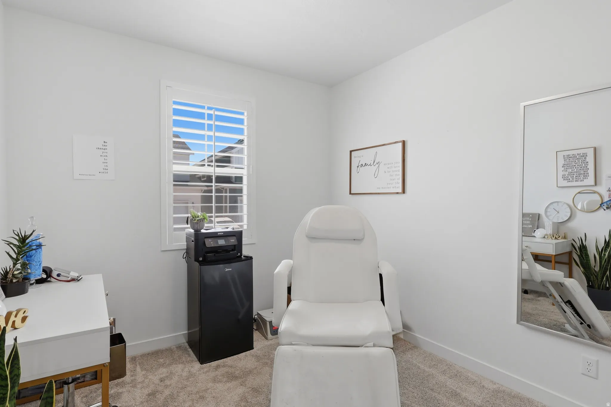 Carpeted room with white walls, featuring a window with white louvered blinds