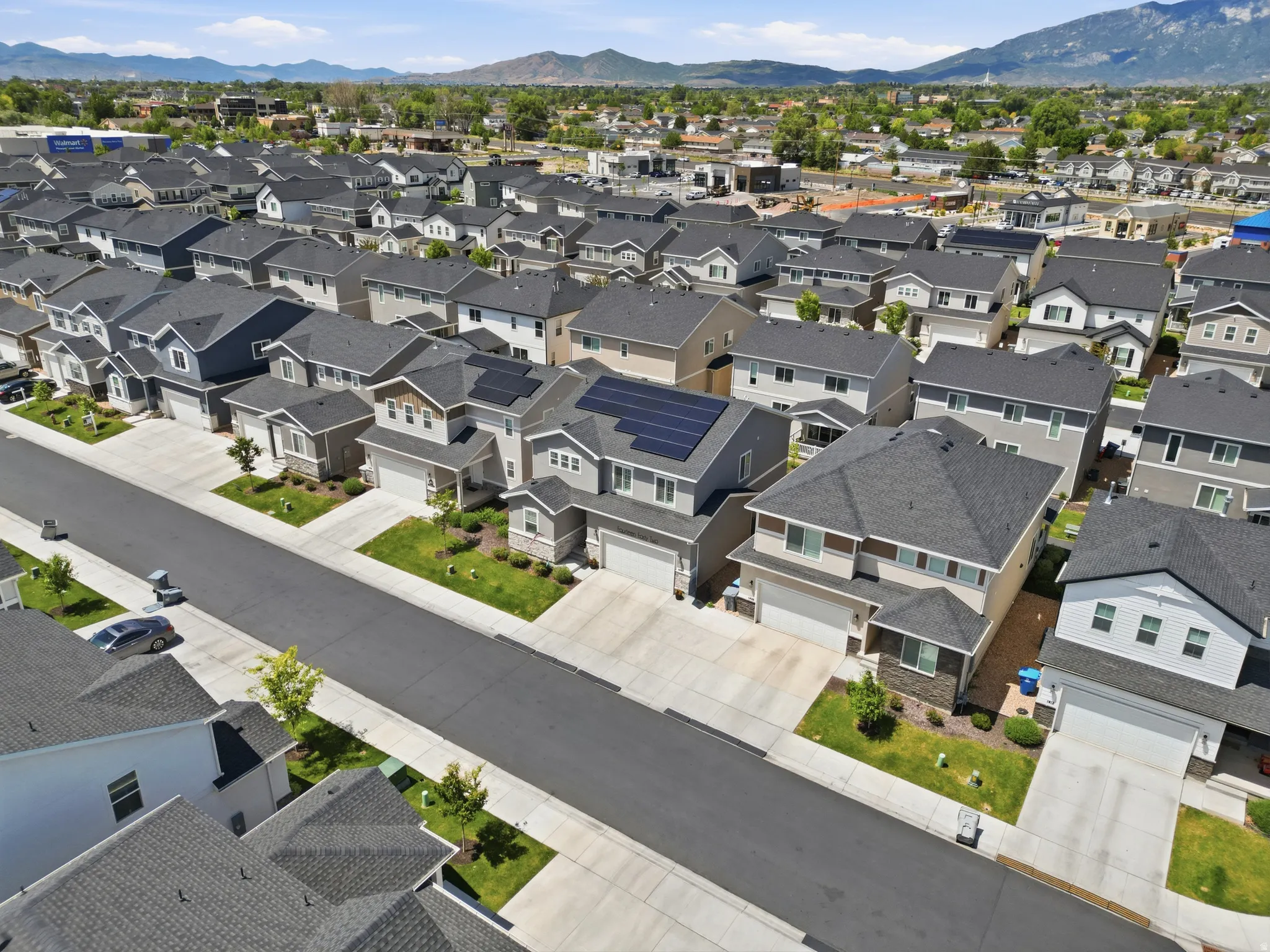 Residential development featuring contemporary homes with dark shingle roofing and light-toned siding