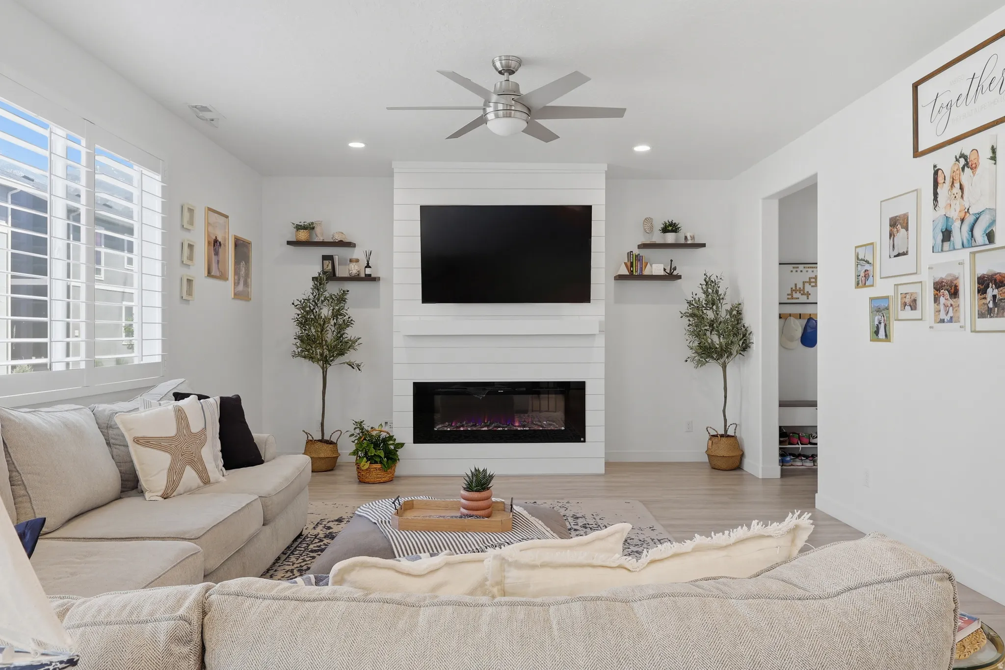 Spacious living area featuring light wood-finish flooring, white walls, and recessed lighting