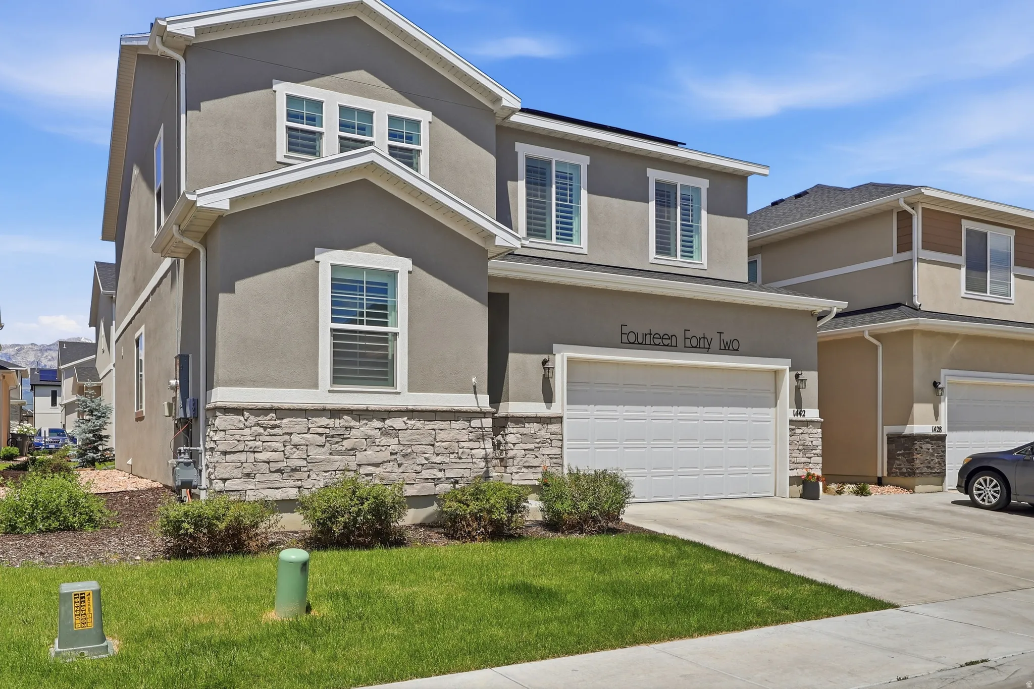 Contemporary two-story exterior featuring stucco siding and stone veneer accents