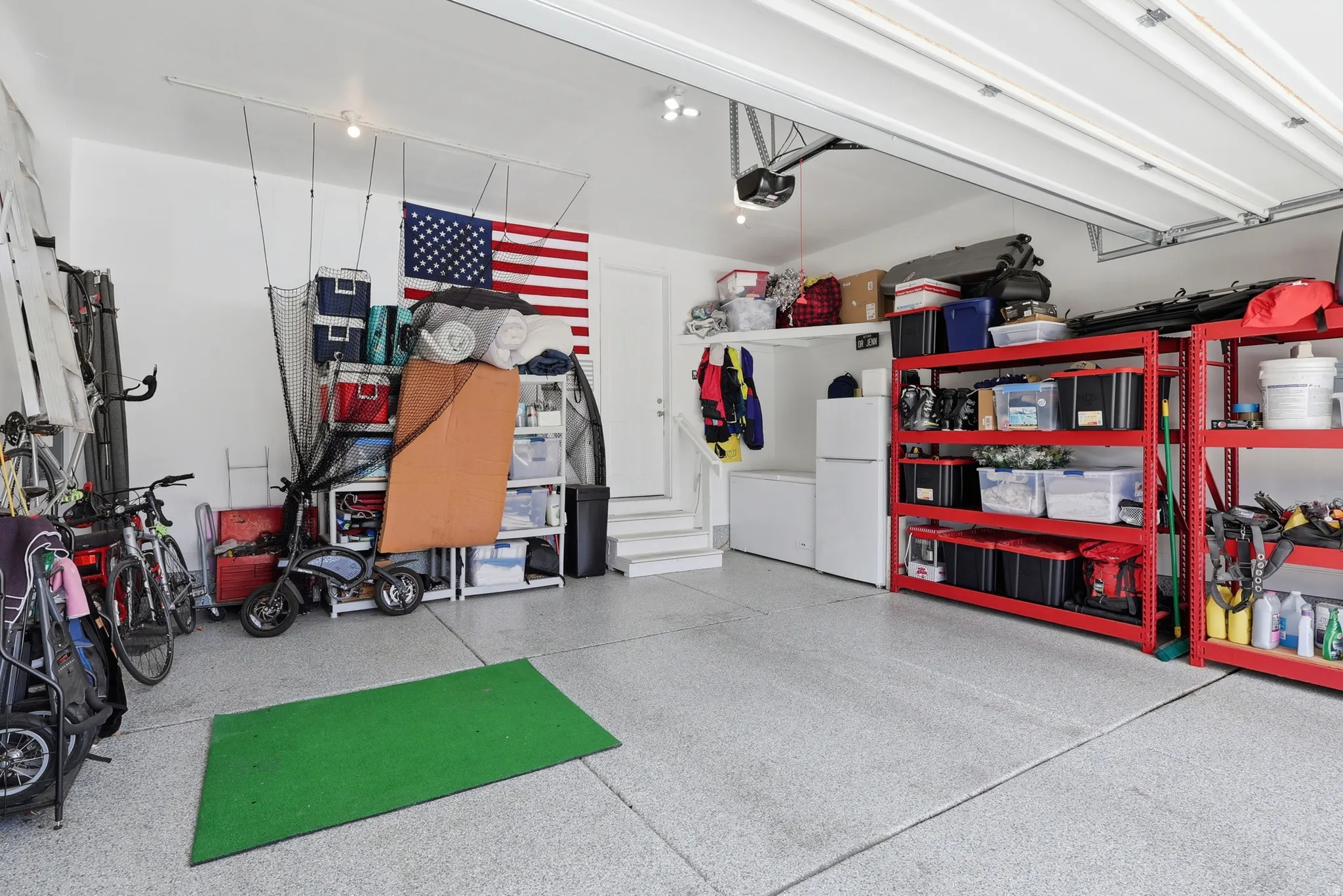 Spacious garage featuring a light-colored epoxy floor, overhead lighting, and white walls