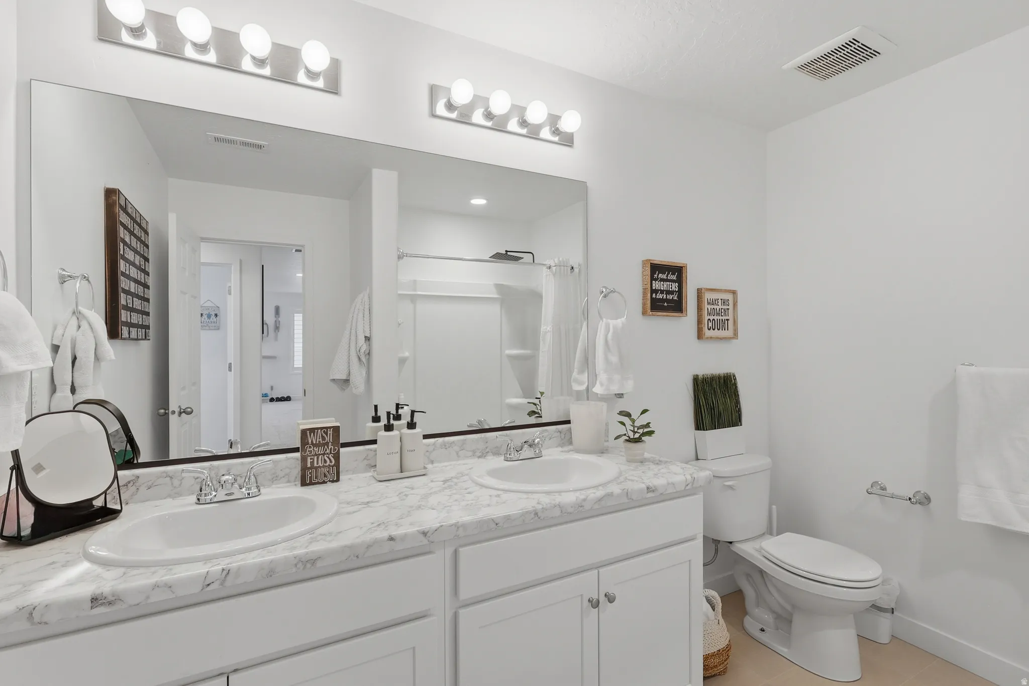 Double vanity featuring white cabinetry, undermount sinks, and marble-look countertops