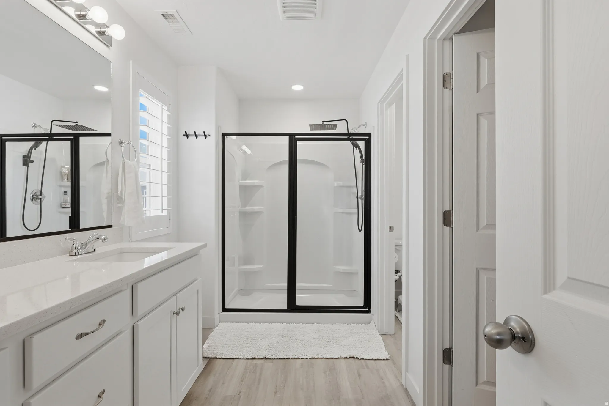 Bathroom featuring a white vanity with an integrated sink, light-colored countertop, and ample storage cabinetry