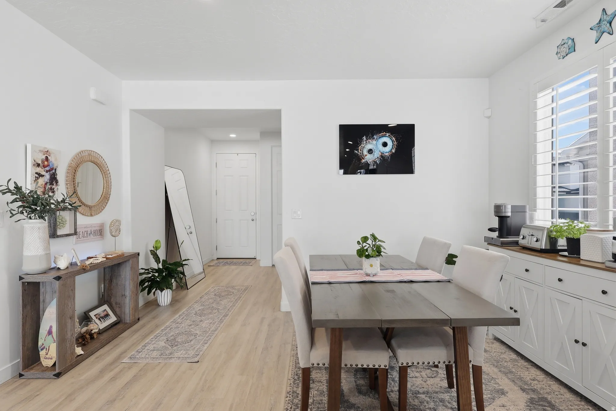 Open-concept room featuring wood-finish flooring, a dining area, and a white built-in console with a wood countertop