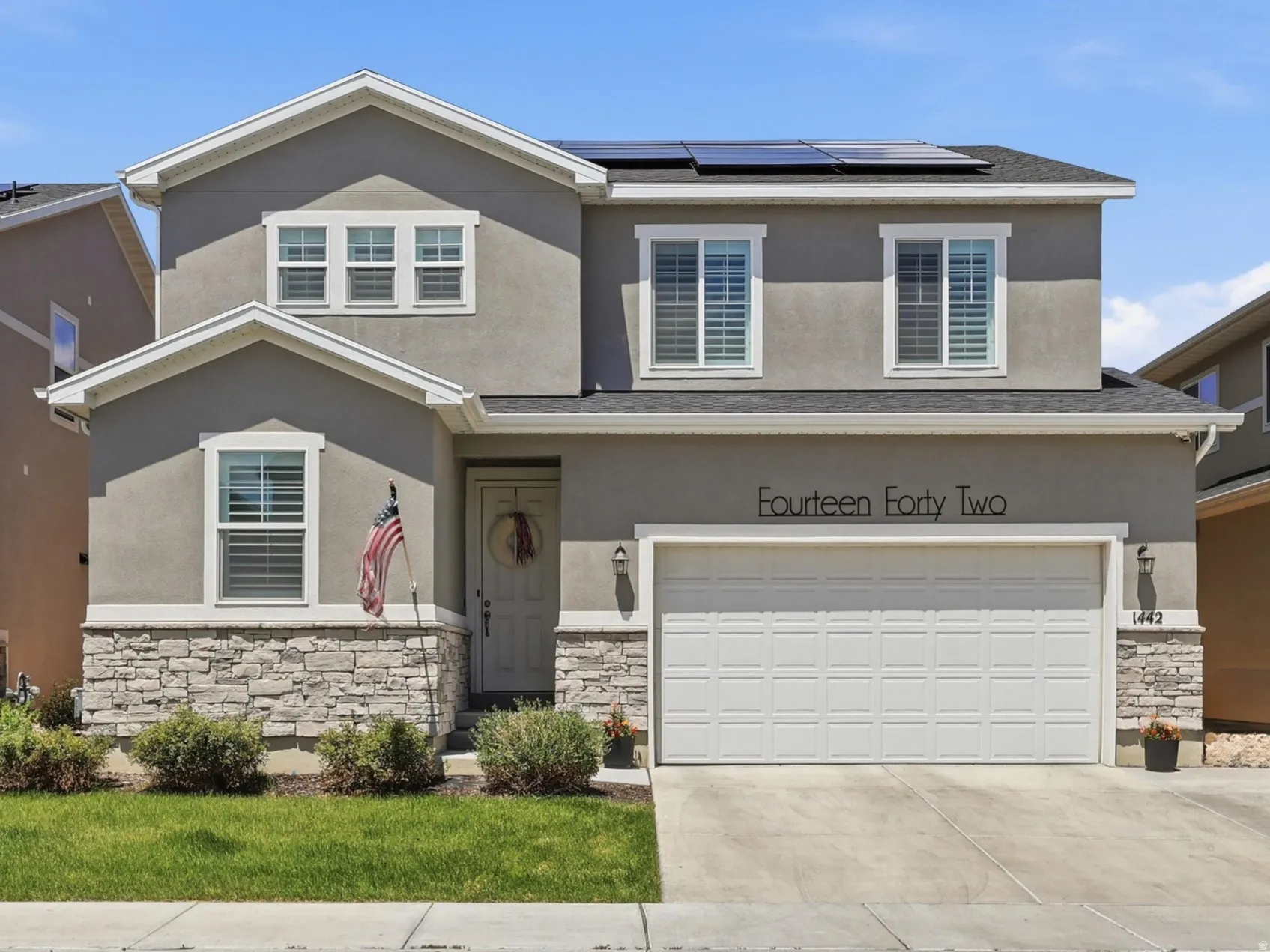 Two-story residence featuring a stucco exterior with stone veneer accents
