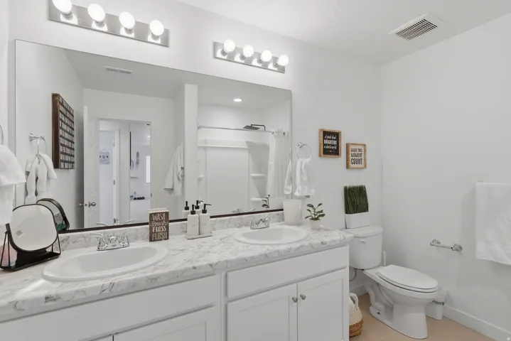 Double vanity featuring white cabinetry, undermount sinks, and marble-look countertops